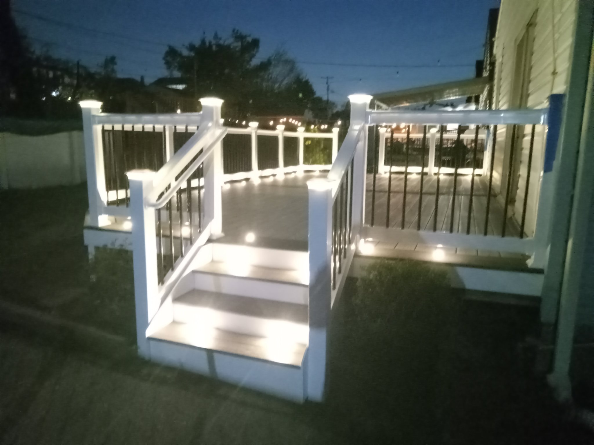 Composite deck with illuminated railing and steps at night